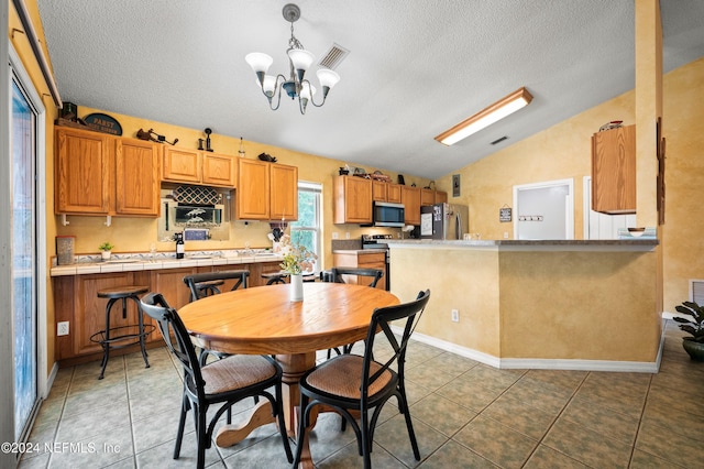 dining room featuring a textured ceiling, dark tile patterned floors, lofted ceiling, and an inviting chandelier