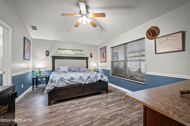 bedroom with ceiling fan, dark hardwood / wood-style flooring, and a textured ceiling