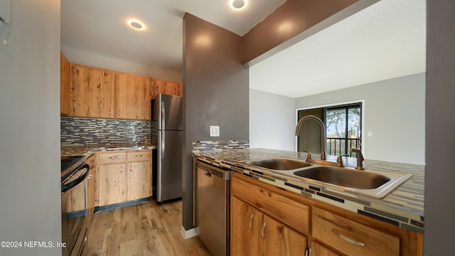 kitchen featuring appliances with stainless steel finishes, tasteful backsplash, light hardwood / wood-style flooring, and sink