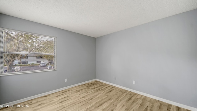 spare room featuring light hardwood / wood-style floors and a textured ceiling