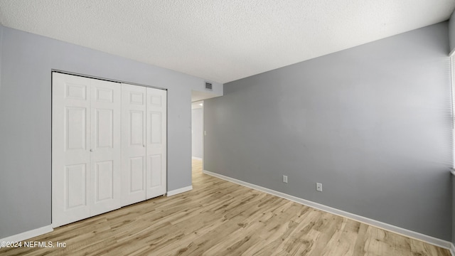 unfurnished bedroom featuring a closet, light hardwood / wood-style flooring, and a textured ceiling