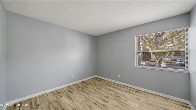 unfurnished room featuring a textured ceiling and light hardwood / wood-style flooring