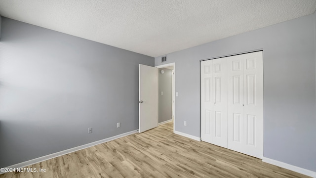 unfurnished bedroom with a closet, a textured ceiling, and light hardwood / wood-style flooring