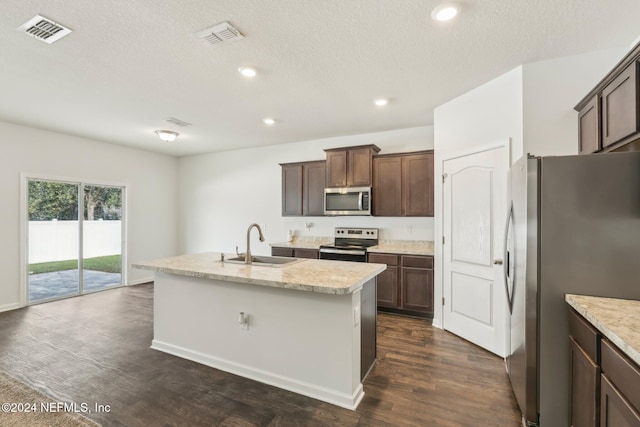 kitchen featuring dark brown cabinetry, sink, dark hardwood / wood-style floors, an island with sink, and appliances with stainless steel finishes