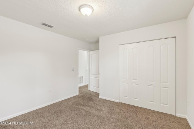 unfurnished bedroom featuring carpet, a textured ceiling, and a closet