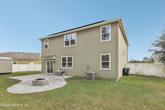 back of house with central AC, an outdoor fire pit, a patio area, and a lawn