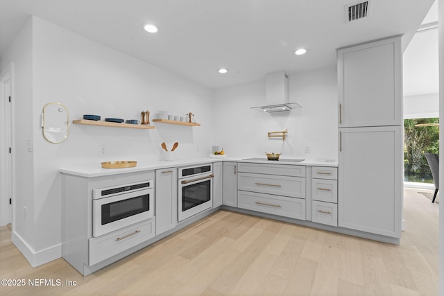 kitchen featuring light hardwood / wood-style flooring, white oven, gray cabinetry, black electric stovetop, and wall chimney exhaust hood