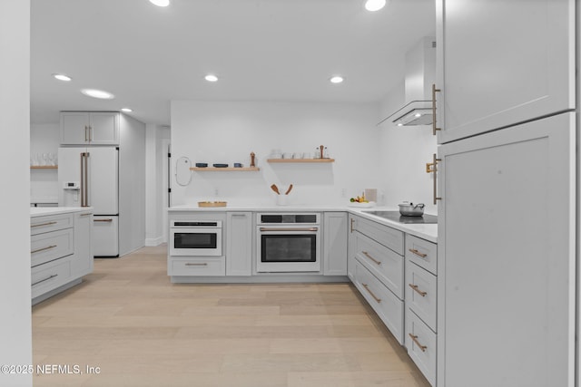 kitchen with white cabinets, white appliances, wall chimney exhaust hood, and light wood-type flooring