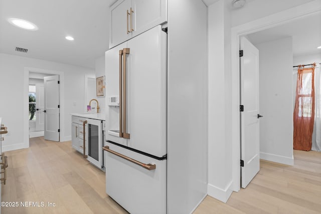 kitchen with white cabinetry, wine cooler, plenty of natural light, and light hardwood / wood-style floors