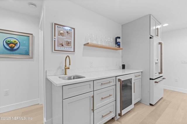 kitchen with wine cooler, sink, high end refrigerator, and light wood-type flooring