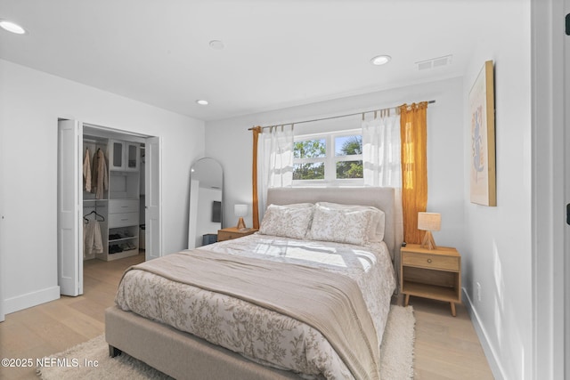 bedroom with a spacious closet and light wood-type flooring