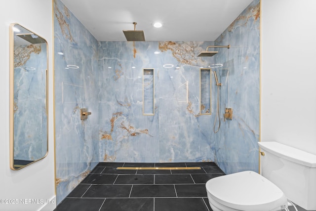 bathroom featuring a tile shower, tile patterned floors, and toilet