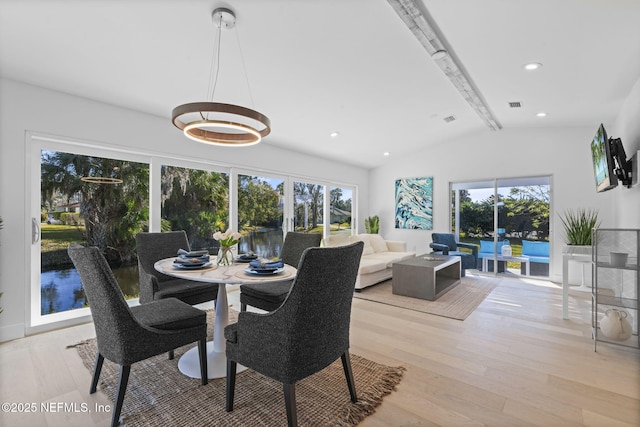 dining room featuring a wealth of natural light, light hardwood / wood-style flooring, and lofted ceiling with beams