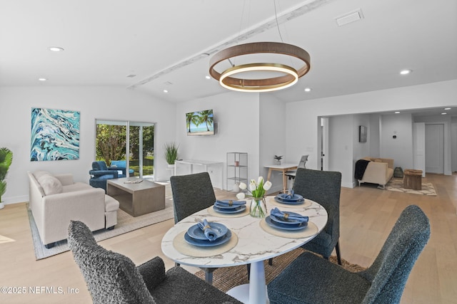 dining room with lofted ceiling, a chandelier, and light wood-type flooring