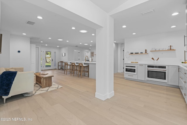 interior space featuring white cabinetry, oven, and light hardwood / wood-style flooring