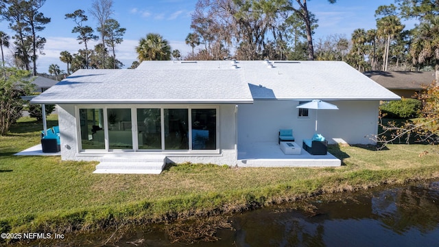 rear view of property featuring a water view, a yard, and a patio area