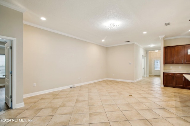 unfurnished living room featuring a wealth of natural light, crown molding, and light tile patterned floors