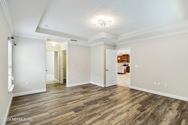 interior space featuring a textured ceiling, a tray ceiling, a healthy amount of sunlight, crown molding, and hardwood / wood-style flooring