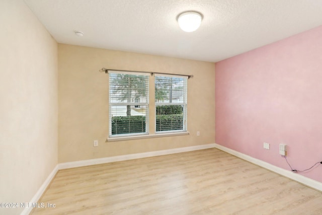 unfurnished room with light wood-type flooring and a textured ceiling