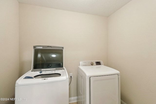 clothes washing area featuring washing machine and clothes dryer and a textured ceiling