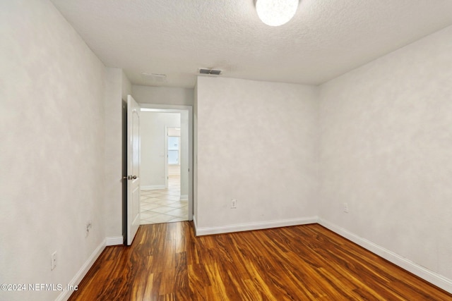 empty room featuring wood-type flooring and a textured ceiling