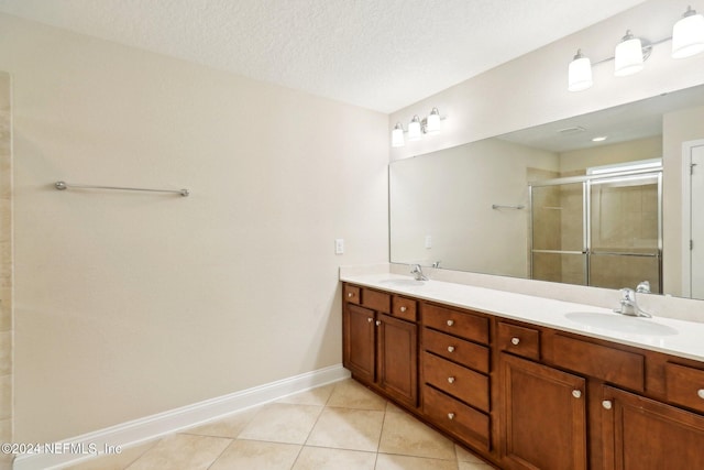 bathroom with tile patterned floors, vanity, a shower with door, and a textured ceiling