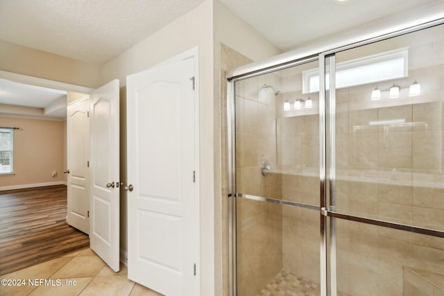 bathroom with hardwood / wood-style flooring, a shower with shower door, and a textured ceiling