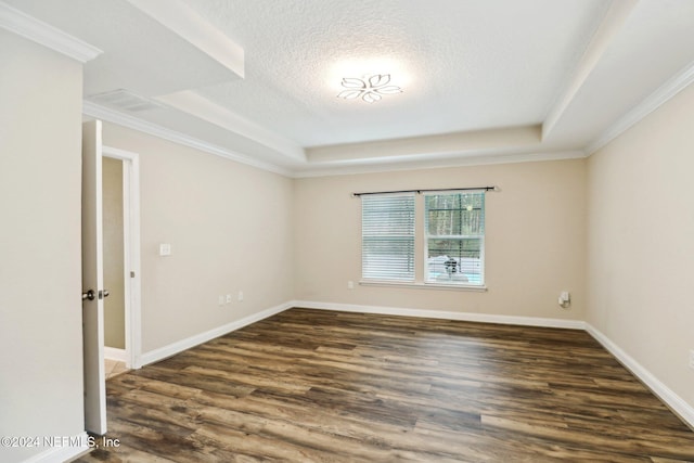 empty room with dark hardwood / wood-style floors, ornamental molding, and a tray ceiling