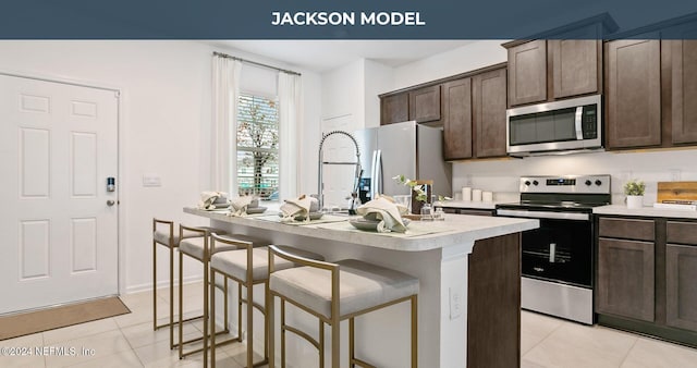 kitchen featuring dark brown cabinetry, a kitchen island with sink, and appliances with stainless steel finishes