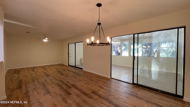 interior space with ceiling fan with notable chandelier and wood-type flooring