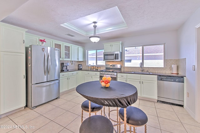 kitchen with appliances with stainless steel finishes, backsplash, a raised ceiling, sink, and light tile patterned floors