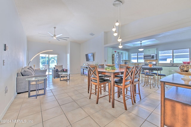 dining area featuring ceiling fan, light tile patterned flooring, lofted ceiling, and sink