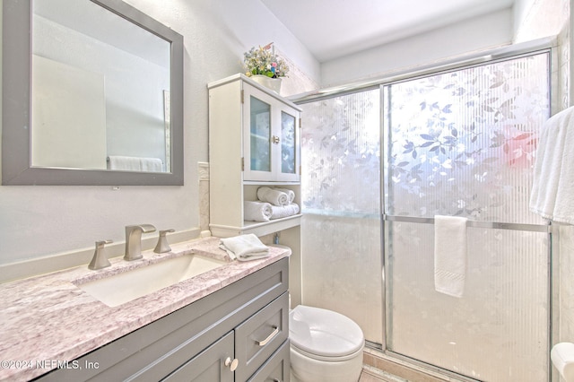 bathroom with vanity, toilet, and a shower with door