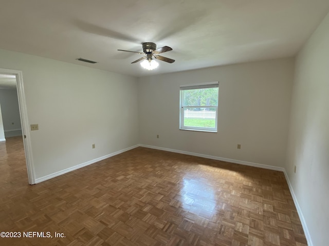 spare room featuring ceiling fan and dark parquet floors