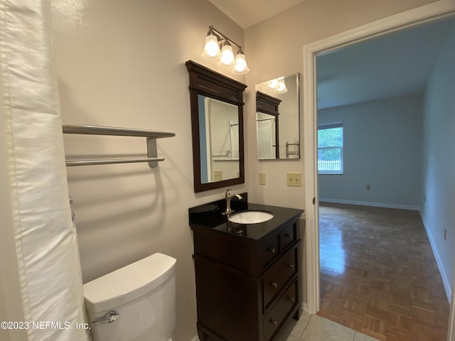 bathroom with toilet, vanity, and parquet flooring