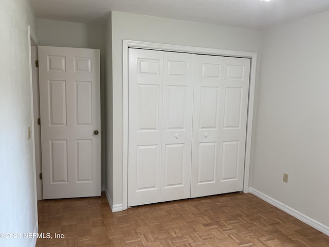 unfurnished bedroom featuring light parquet flooring and a closet