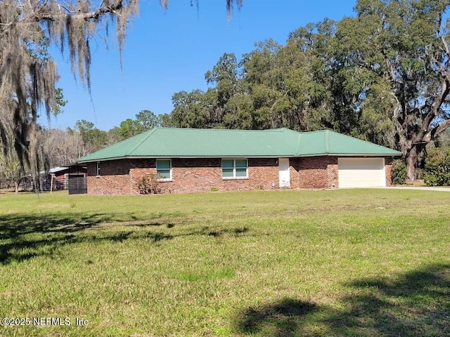 view of home's exterior with an attached garage, brick siding, metal roof, and a yard