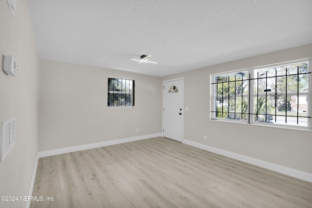 empty room with light hardwood / wood-style floors and a textured ceiling