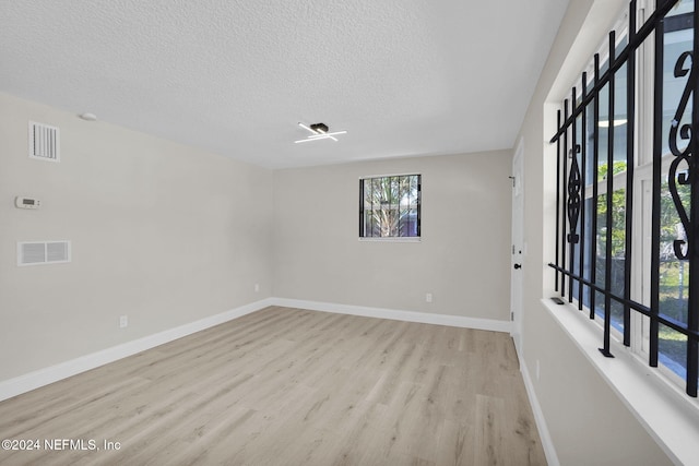 spare room featuring light hardwood / wood-style floors and a textured ceiling