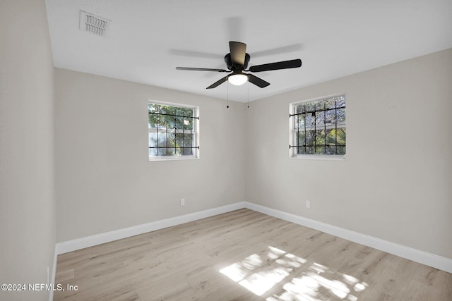 spare room with ceiling fan, light wood-type flooring, and a wealth of natural light