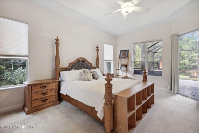 bedroom featuring a raised ceiling, ceiling fan, access to exterior, and light carpet