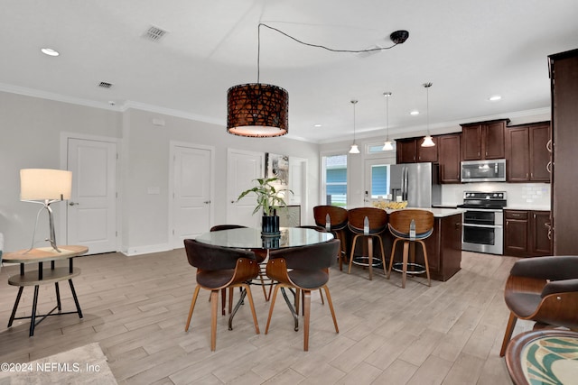 dining area featuring light wood-type flooring and ornamental molding