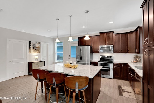 kitchen featuring hanging light fixtures, stainless steel appliances, light stone counters, light hardwood / wood-style flooring, and a kitchen island