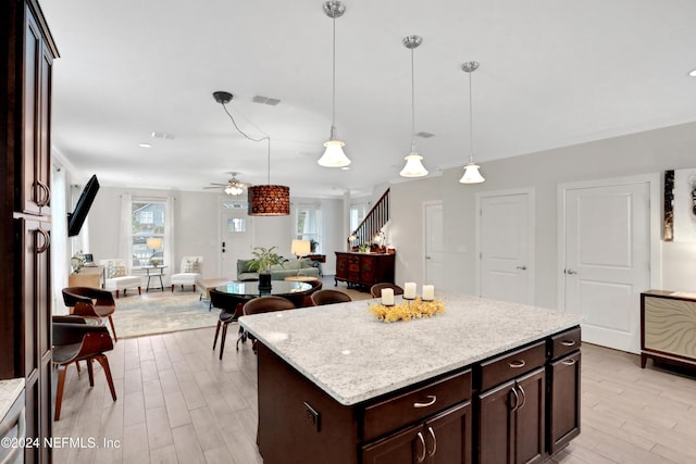 kitchen with hanging light fixtures, light hardwood / wood-style flooring, ceiling fan, dark brown cabinets, and a kitchen island