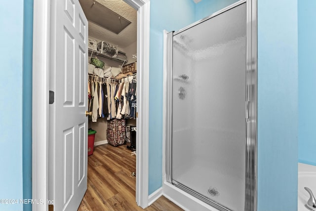 bathroom featuring hardwood / wood-style floors, a textured ceiling, and a shower with shower door