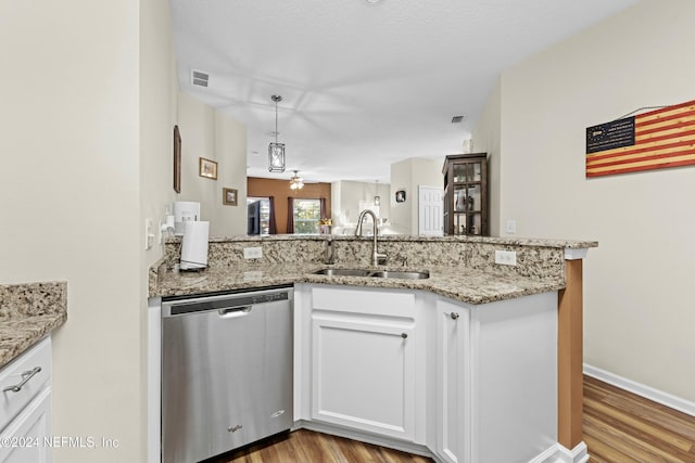 kitchen with kitchen peninsula, light wood-type flooring, stainless steel dishwasher, sink, and white cabinetry