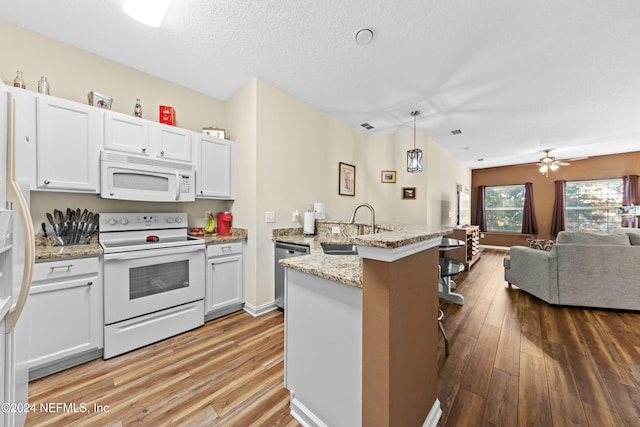 kitchen with white appliances, sink, hardwood / wood-style flooring, decorative light fixtures, and white cabinetry