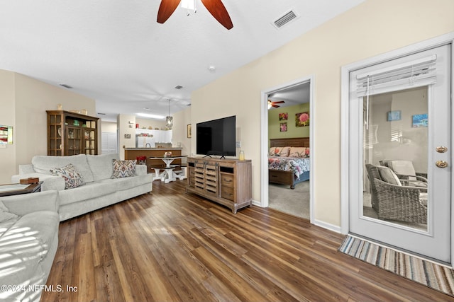 living room featuring a textured ceiling, ceiling fan, and dark wood-type flooring