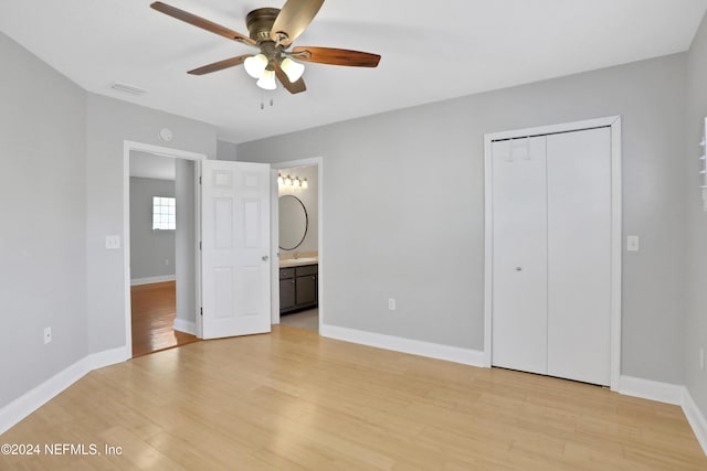 unfurnished bedroom with light wood-type flooring, a closet, ensuite bathroom, and ceiling fan