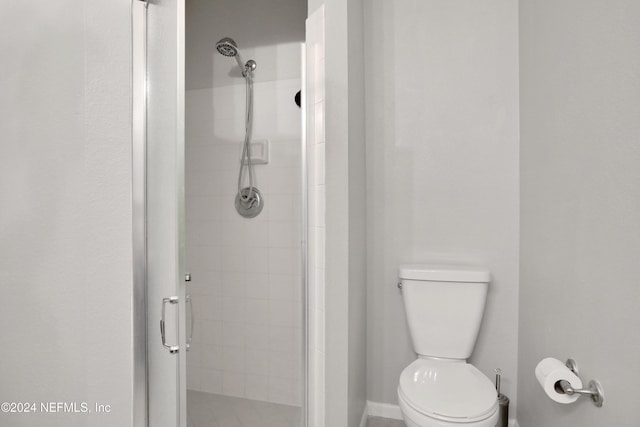 bathroom featuring toilet and a shower with shower door